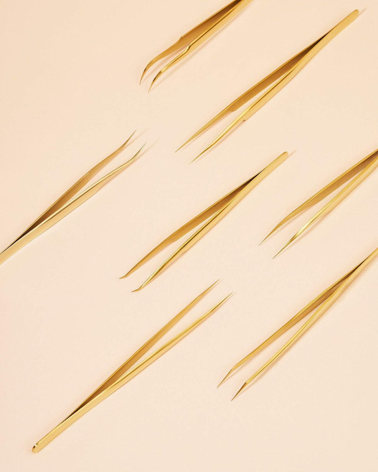 Diagonal golden slash marks or scratches on a beige textured background create an abstract pattern.