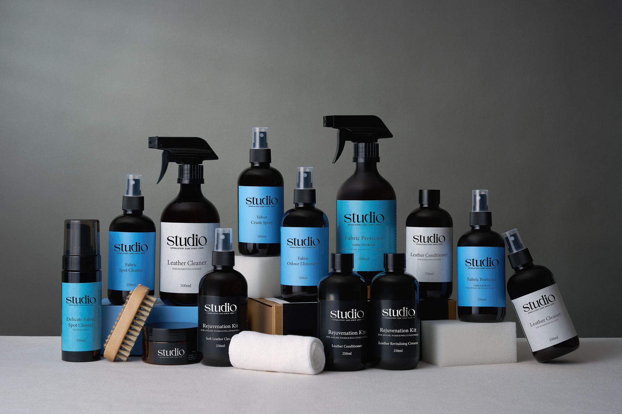 Collection of luxury black and blue branded beauty product bottles and containers arranged in a sleek display lineup.