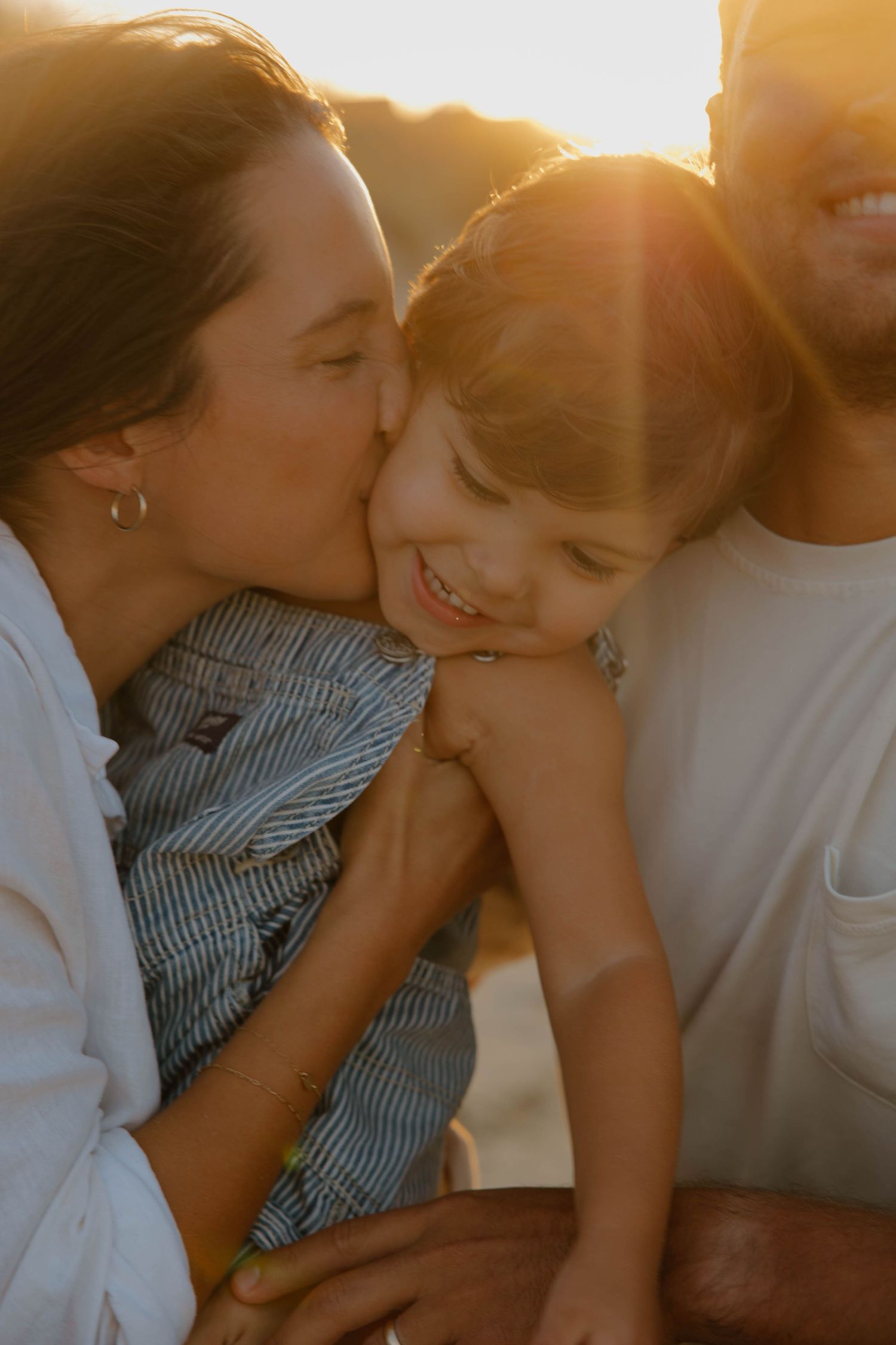 Tender family moment captured in golden sunset light.