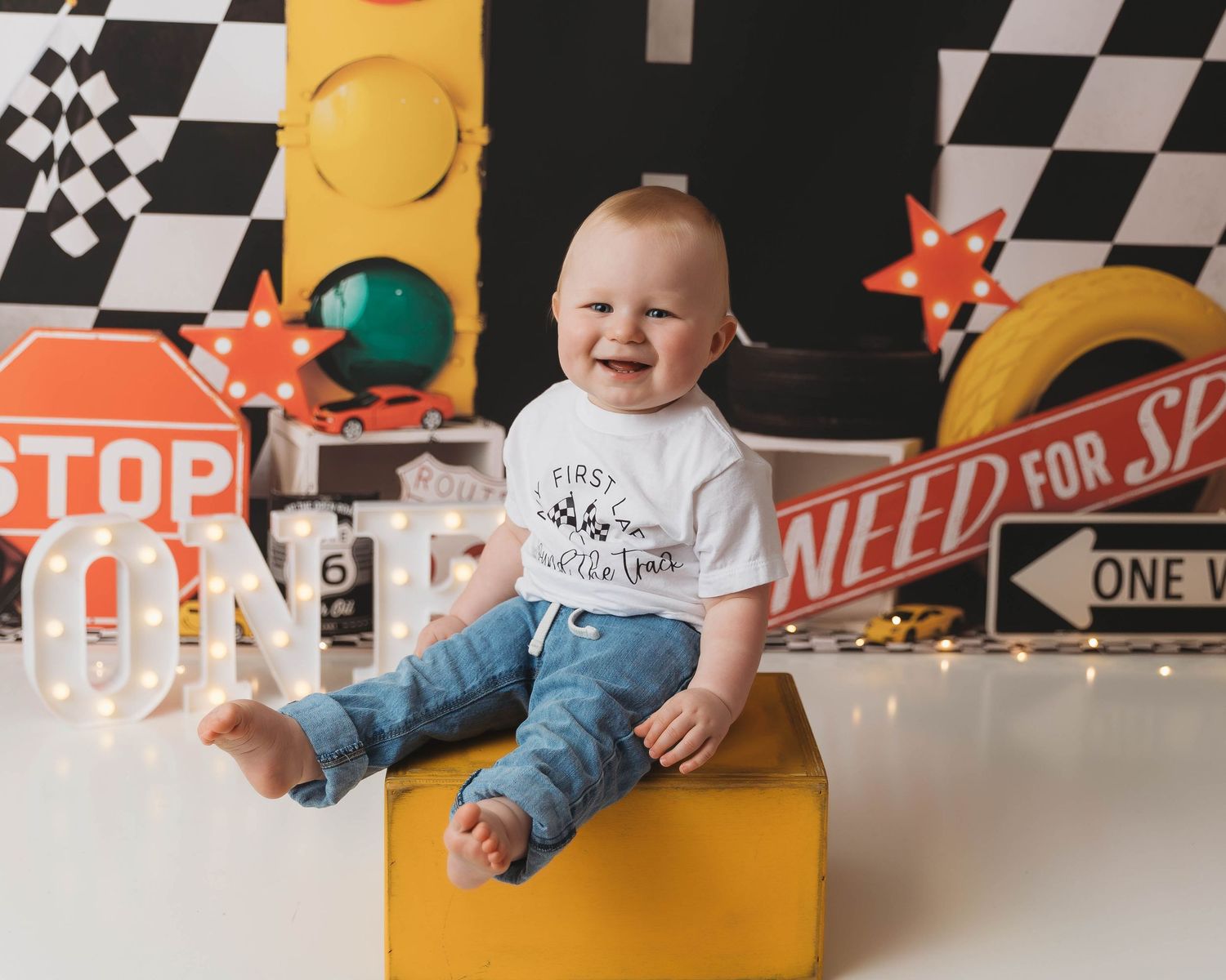 Racing themed baby photo session with checkered flags and yellow accents.