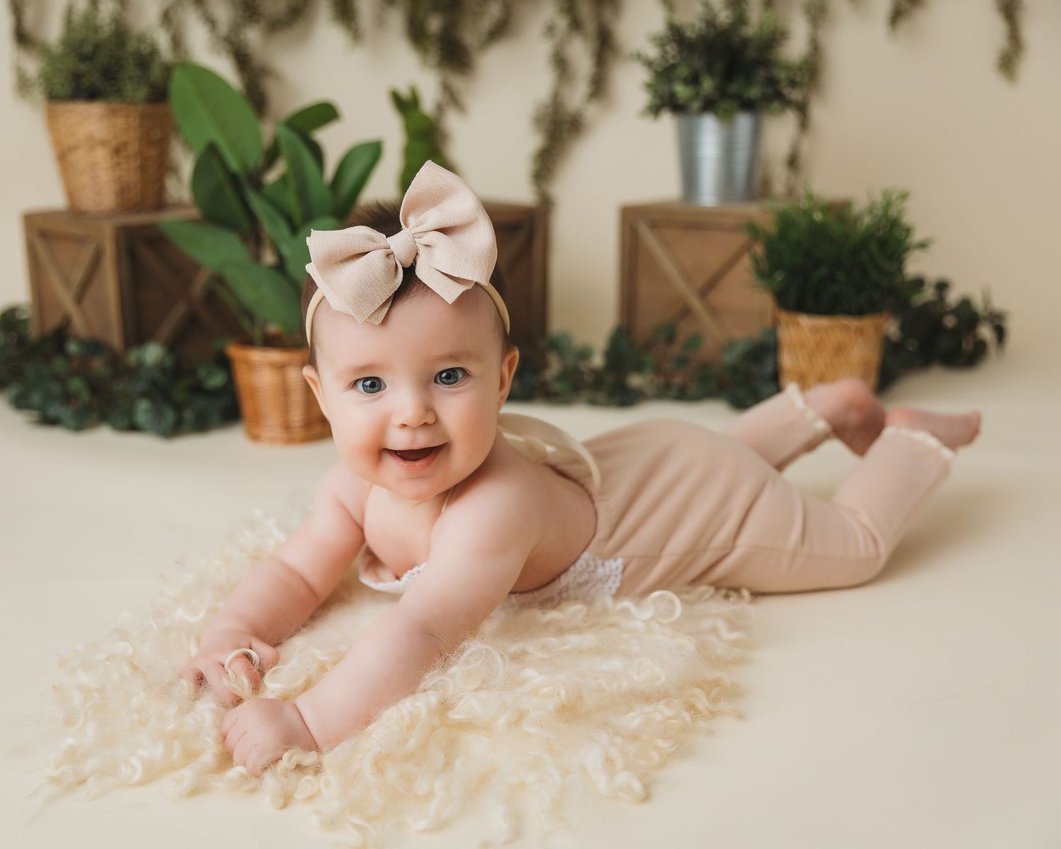 Baby milestone photo with natural greenery and wooden decor elements.