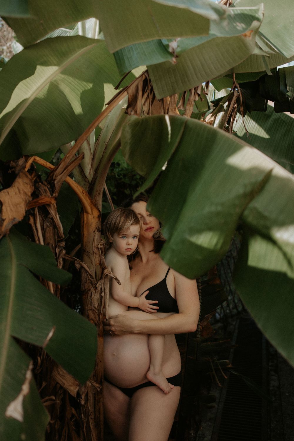 Intimate portrait beneath tropical banana leaves in natural light.