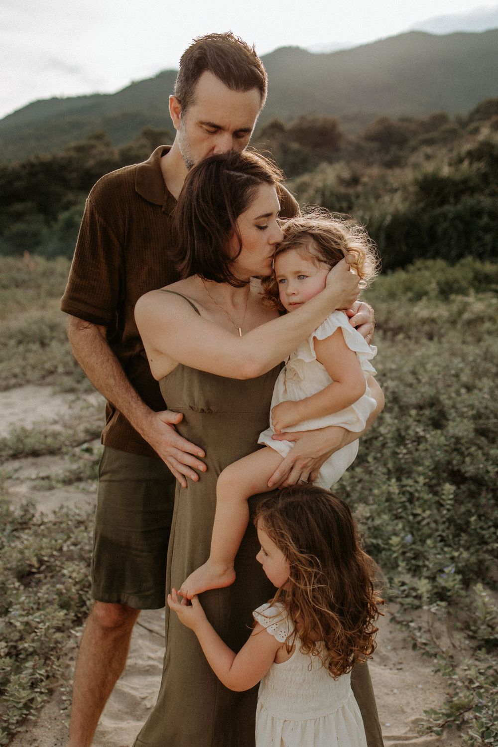 An intimate outdoor family portrait with mountains and natural scenery in the background.
