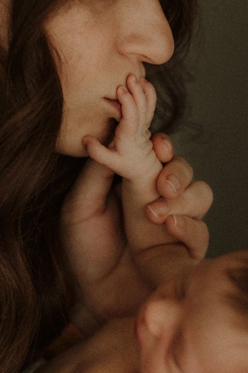 A close-up artistic photo capturing a tiny hand reaching up in intimate lighting.
