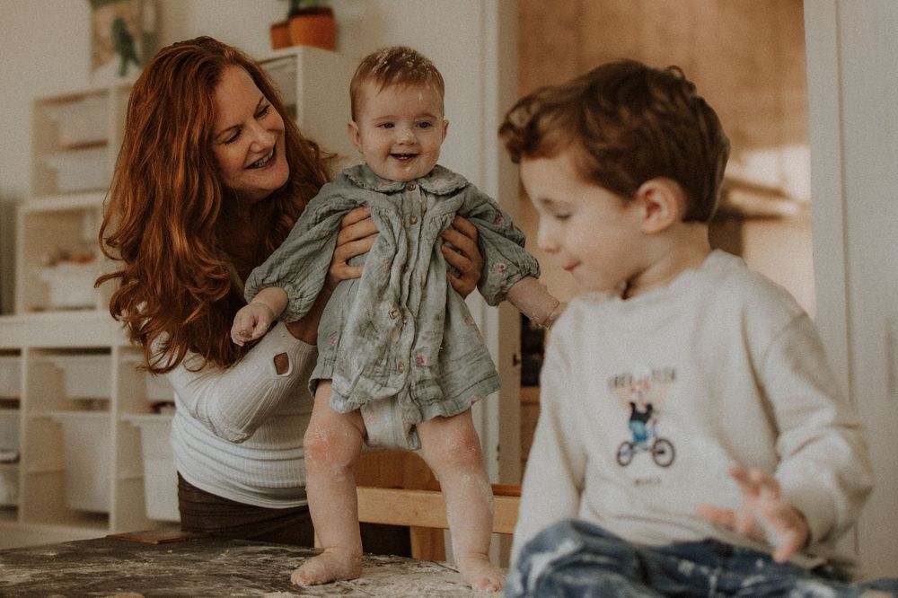 A warm indoor family scene shows people sharing a joyful moment together in a cozy home kitchen setting.