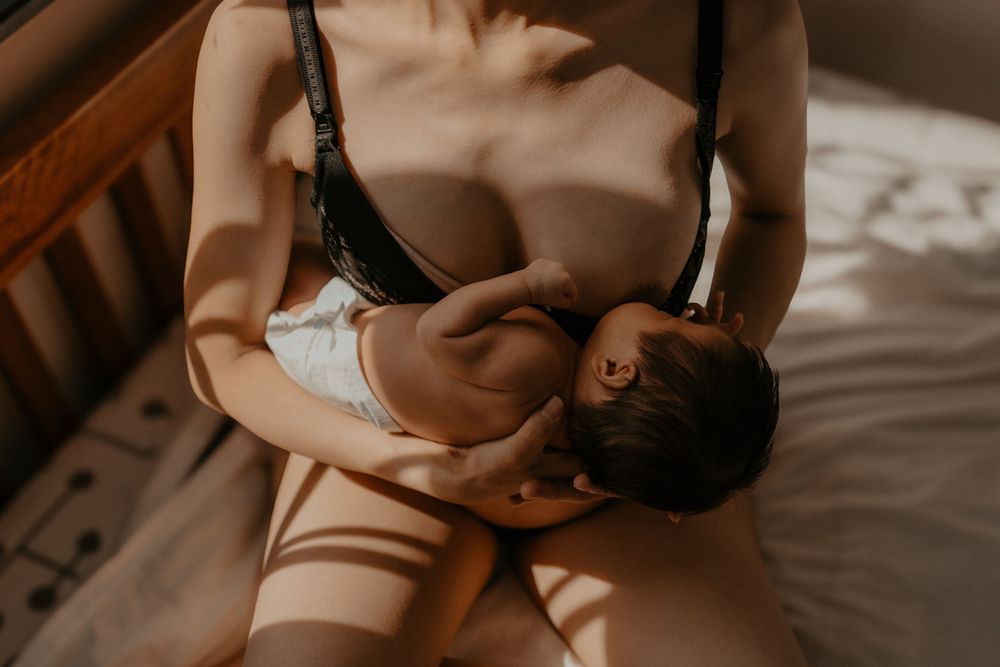 Mother nursing infant in warm, intimate lighting.