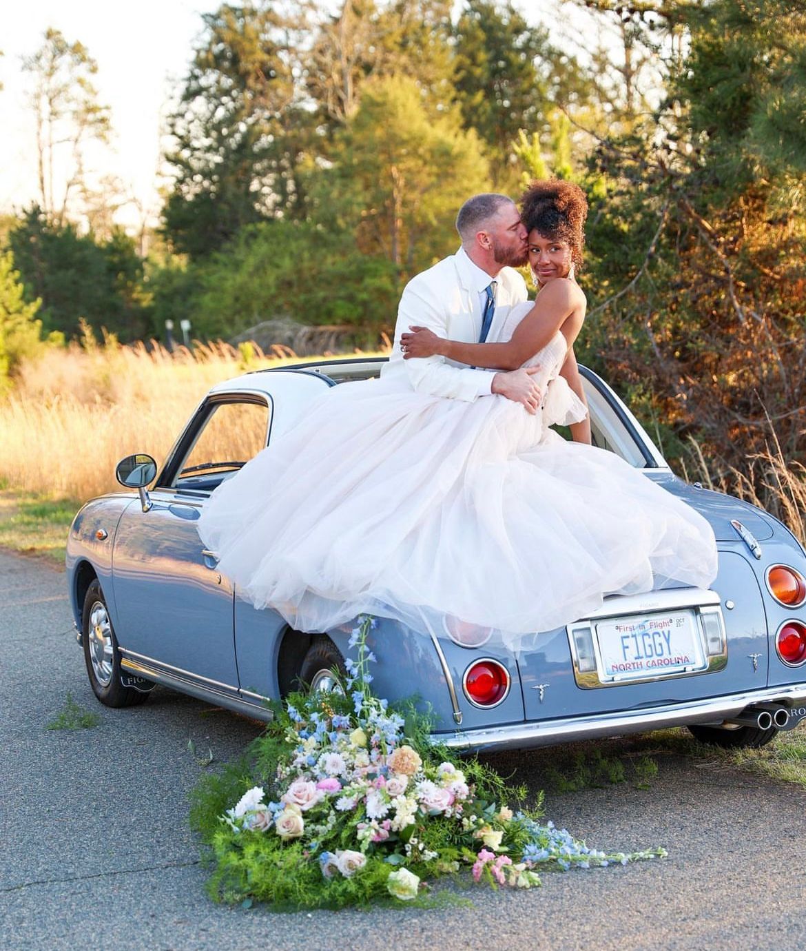 Classic blue convertible car decorated with flowers for wedding photos at sunset.