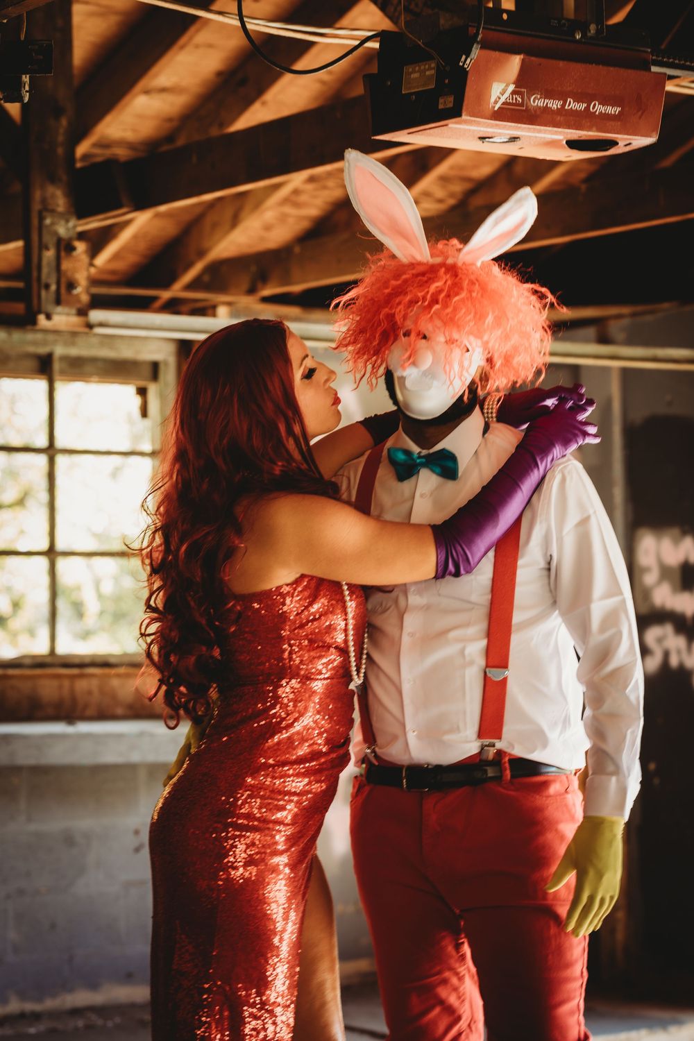 A couple in red dress and white shirt with suspenders dance together in an industrial space.