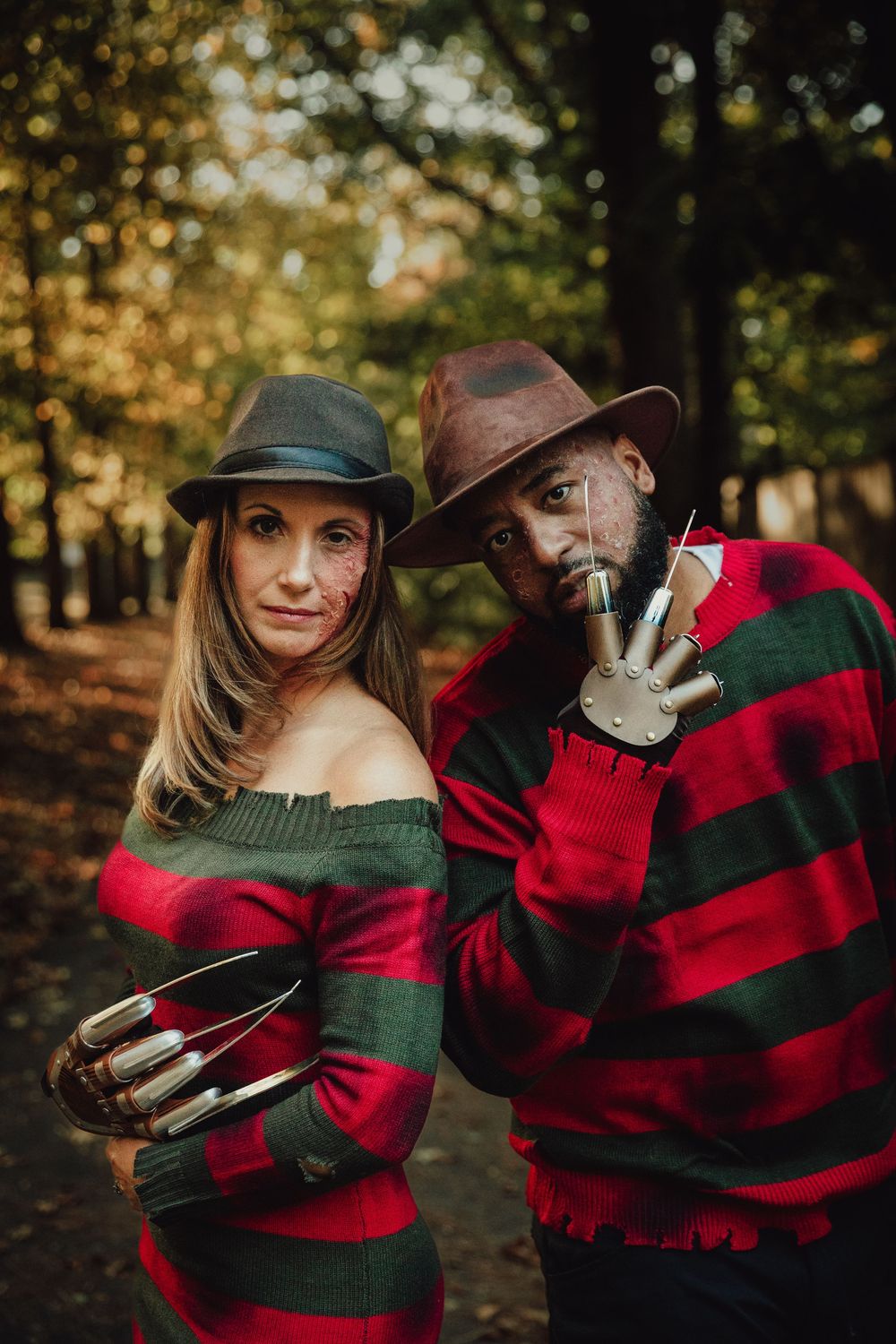 A couple wearing red and black buffalo plaid embraces in an autumn forest setting during a photoshoot.
