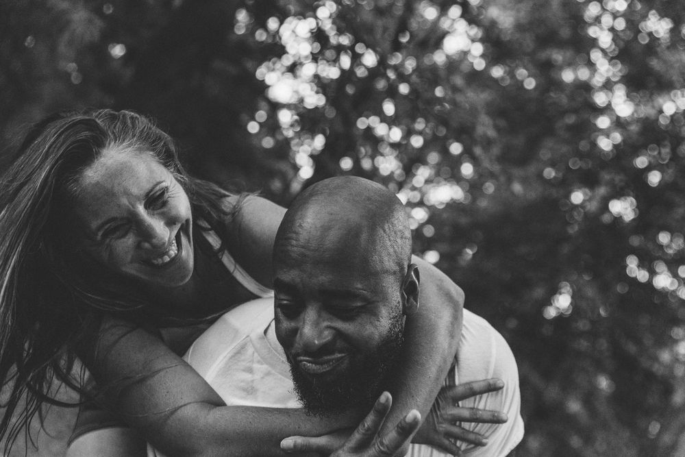 A couple shares a joyful moment together outdoors in black and white photography.