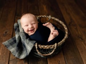 Newborn baby in a basket smiling so big in navy. Greenville, SC newborn photographer, Easley, SC Newborn photographer