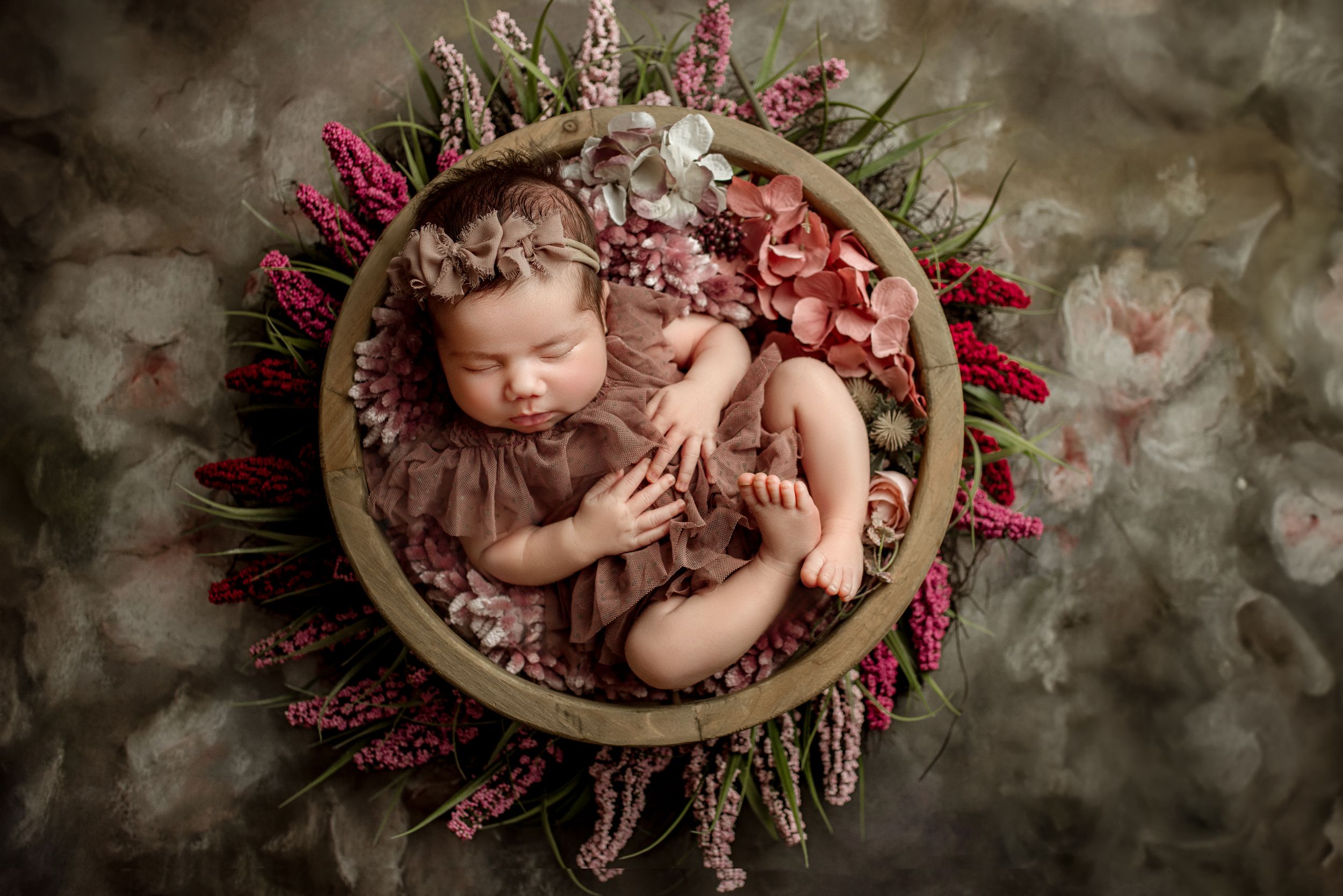 newborn baby girl asleep in a wooden bowl on a floral backdrop captured by cedar park newborn photographer