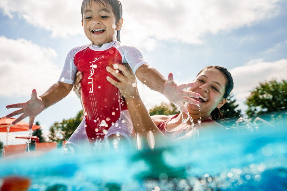 Playful summer scene at a swimming pool with splashing water and joyful expressions captured from underwater perspective.