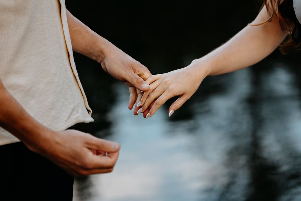 Close-up of hands holding each other against a moody blue background.