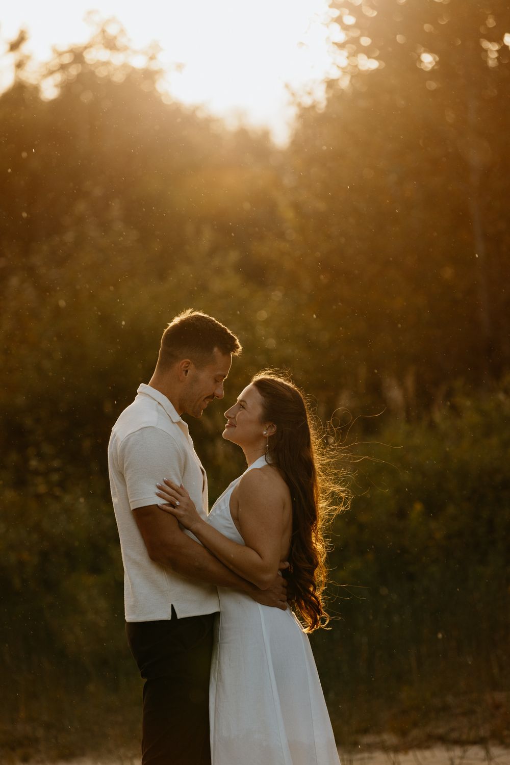 Couple embracing in golden sunset light with bokeh effect.
