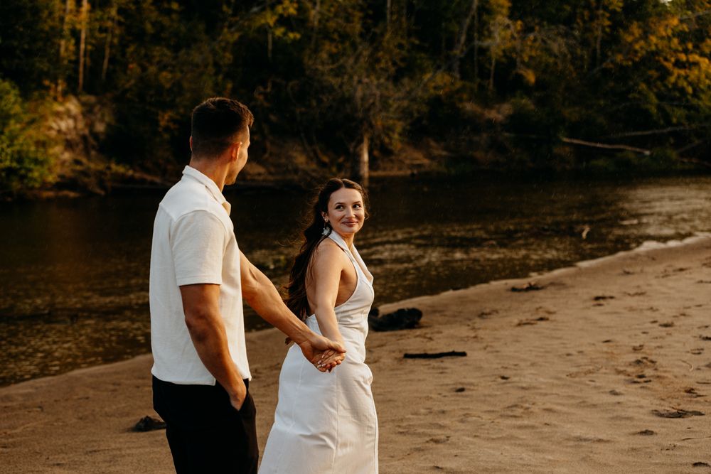 A couple embraces on a beach during golden hour with warm autumn lighting.