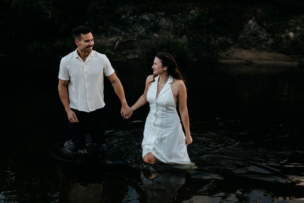 Couple walking hand in hand along a rocky shoreline.