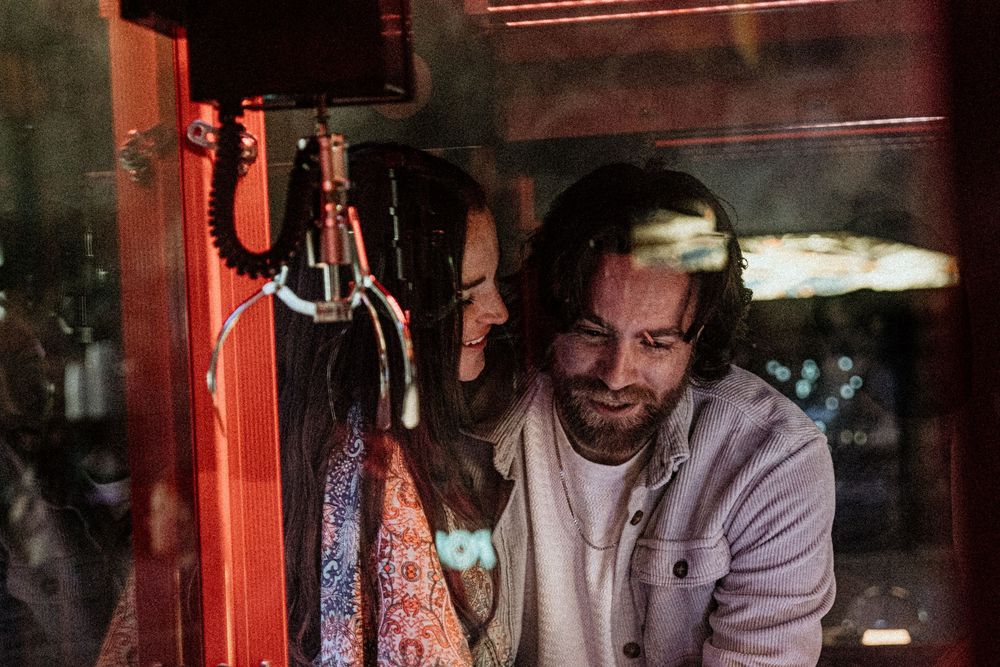 A series of people in a dimly lit space with red lighting creating a moody atmospheric effect.