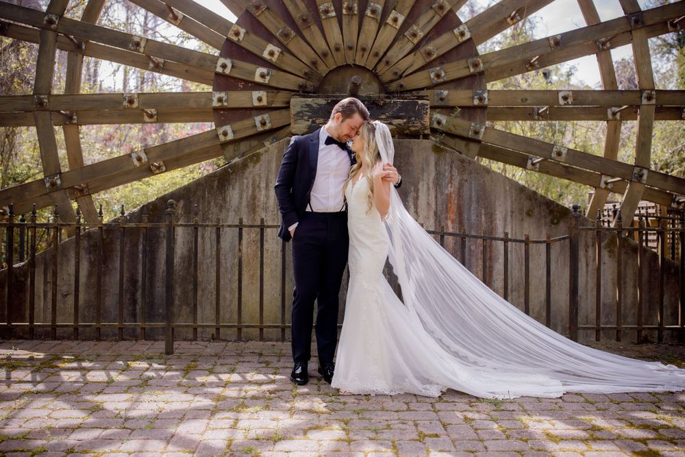A romantic wedding photo in a wooden tunnel structure with dramatic lighting.