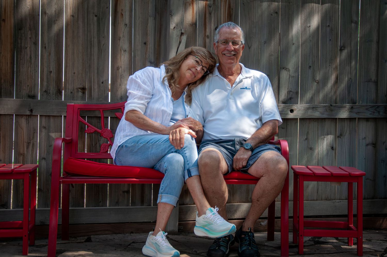 A husband and wife pose on a red bench