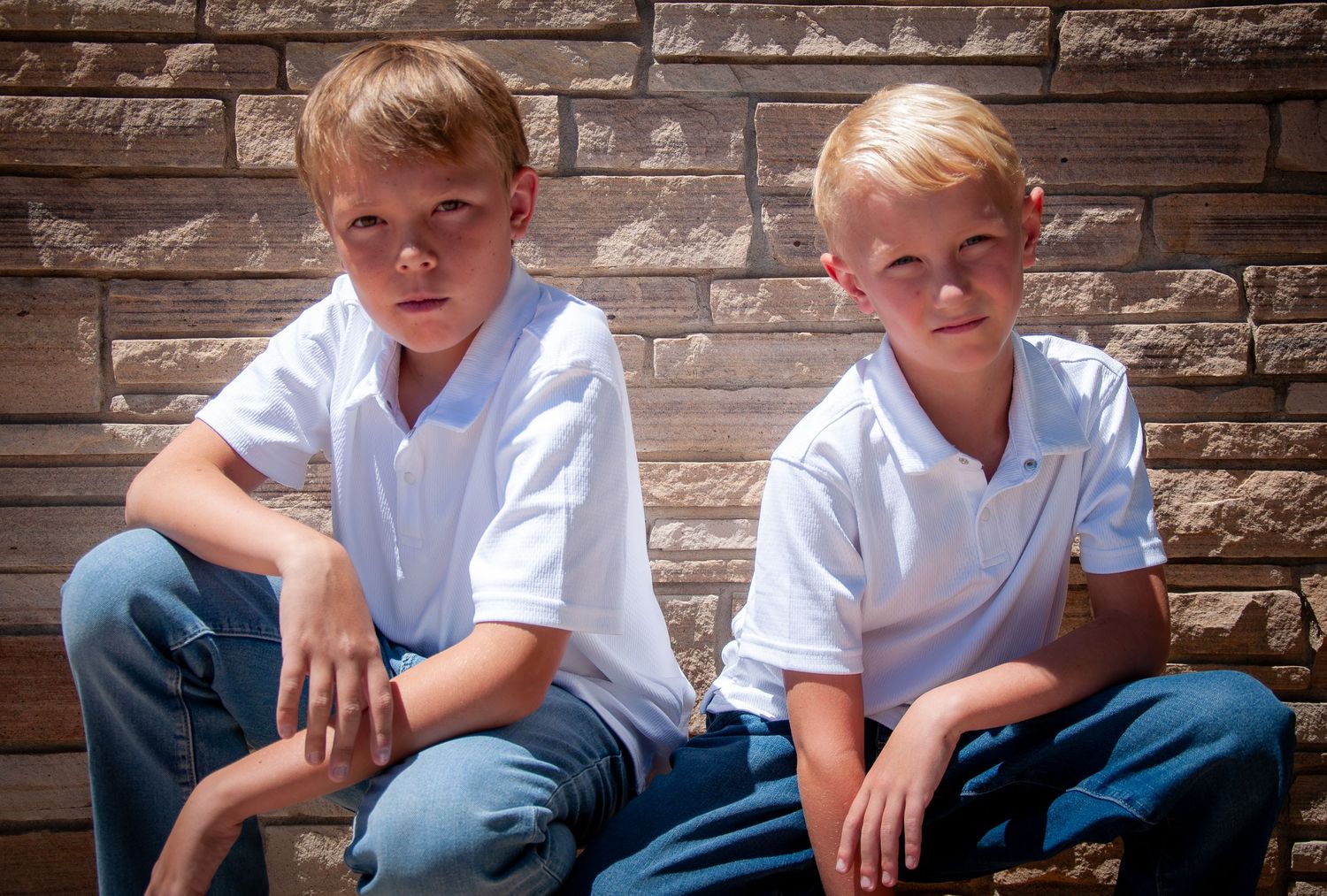 brothers pose in front of a brick wall