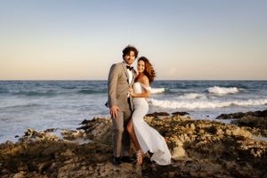 Romantic wedding photography session on rocky beach at sunset.