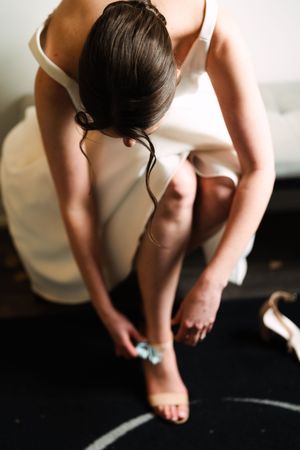 Close-up of someone in white dress adjusting their shoe.