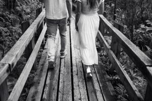 Couple walking on rustic wooden bridge through nature.