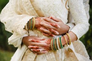 Close-up of hands adorned with traditional Indian wedding bangles and jewelry.