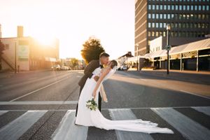 Wedding couple poses in urban setting during golden hour.
