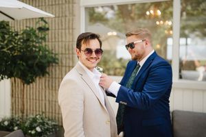 Two people in formal wear sharing a lighthearted moment outside a building.