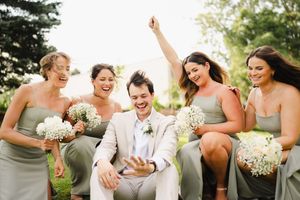 Wedding party laughing and celebrating together outdoors with baby's breath bouquets.