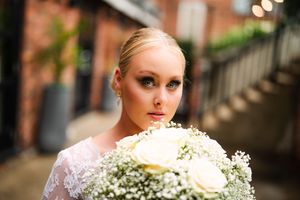 Wedding bouquet with delicate white baby's breath flowers against brick background.