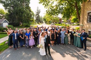 Large wedding party group photo taken outdoors with guests gathered on stone steps.