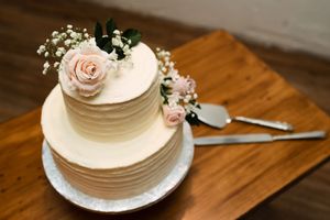 Elegant white wedding cake with delicate floral decorations displayed on wooden table.