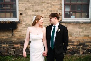 Couple shares intimate moment against historic brick building exterior.
