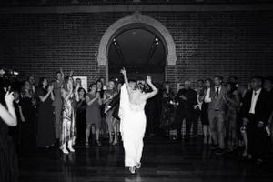 A couple dances together during their wedding reception in a grand ballroom with brick archways.