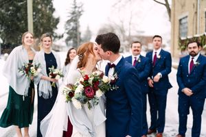 Winter wedding ceremony outdoors with guests in formal attire against snowy backdrop.