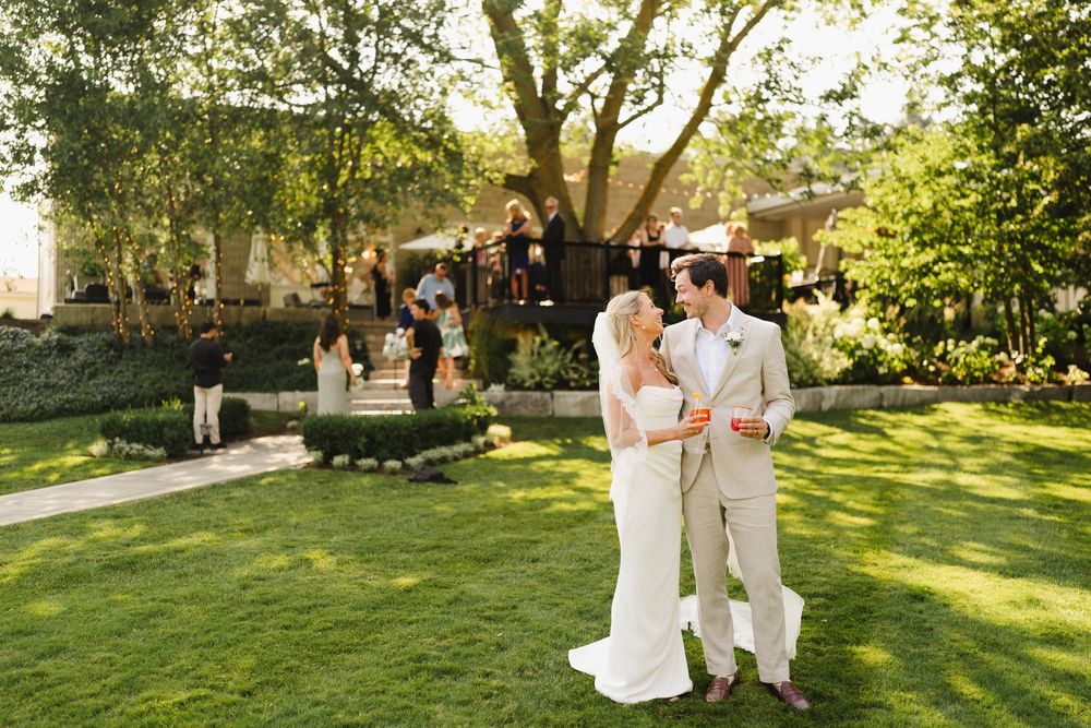 Outdoor wedding ceremony setup with guests gathering on a sunny lawn.