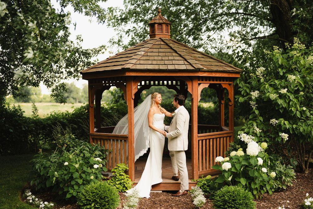 Romantic wedding ceremony moments under a wooden gazebo surrounded by greenery.