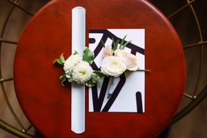 White candle and floral arrangements displayed on deep red circular table.