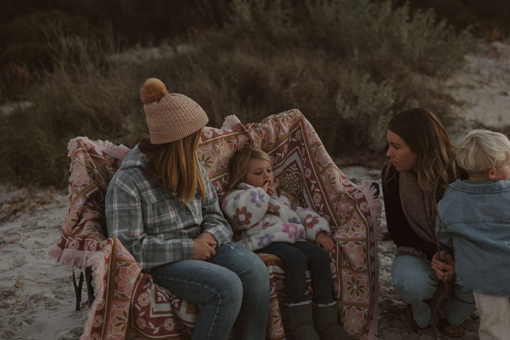Casual beach gathering with blankets and loved ones at twilight.