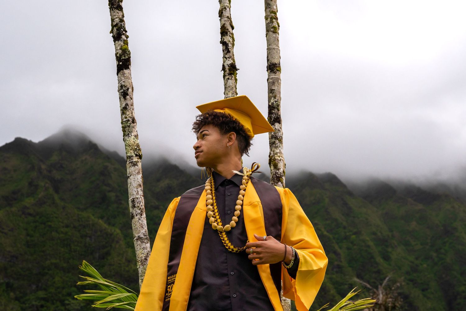 A graduation photographer captures scenic shots in a lush tropical mountain landscape.