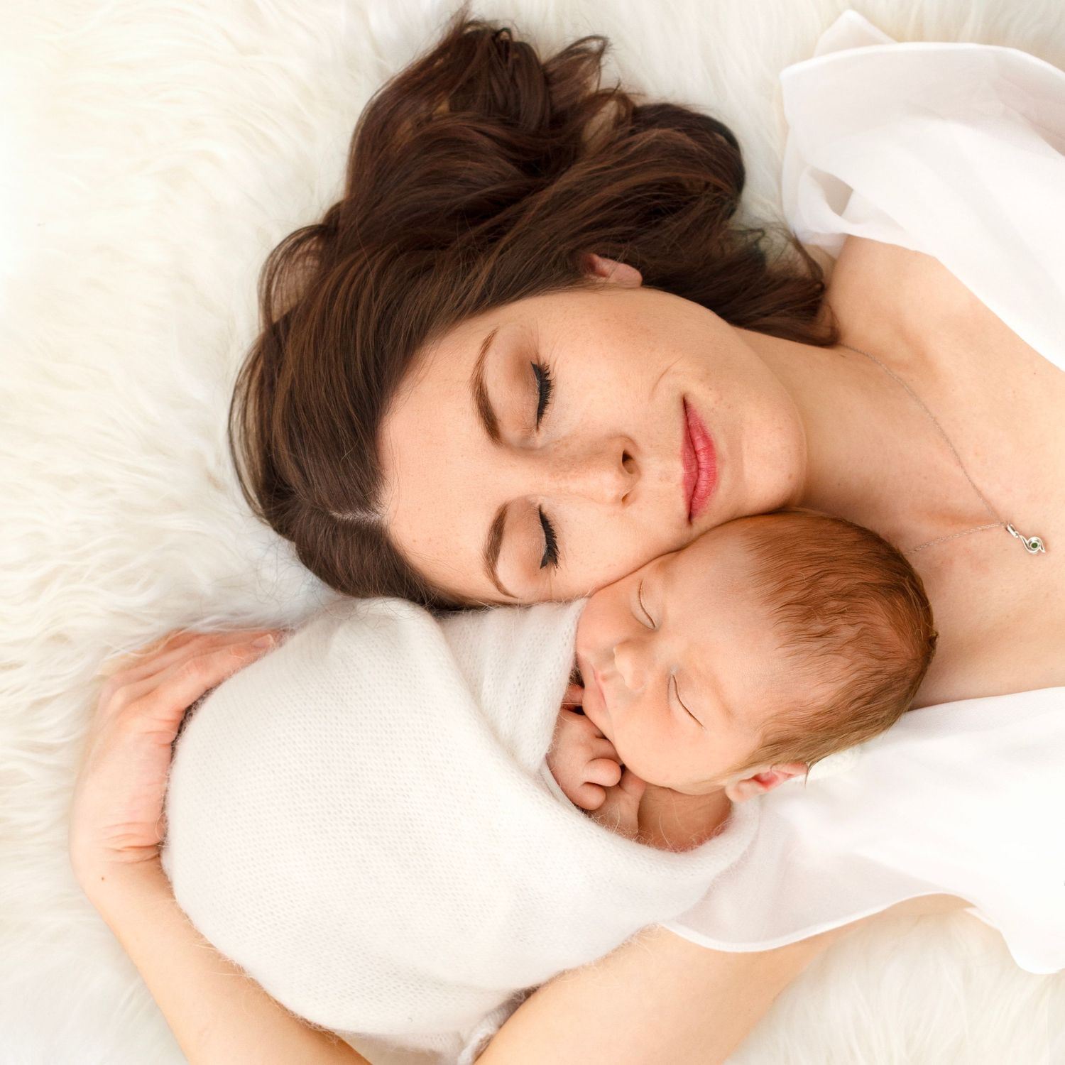 Mother snuggling cheek-to-cheek with her brand new baby boy