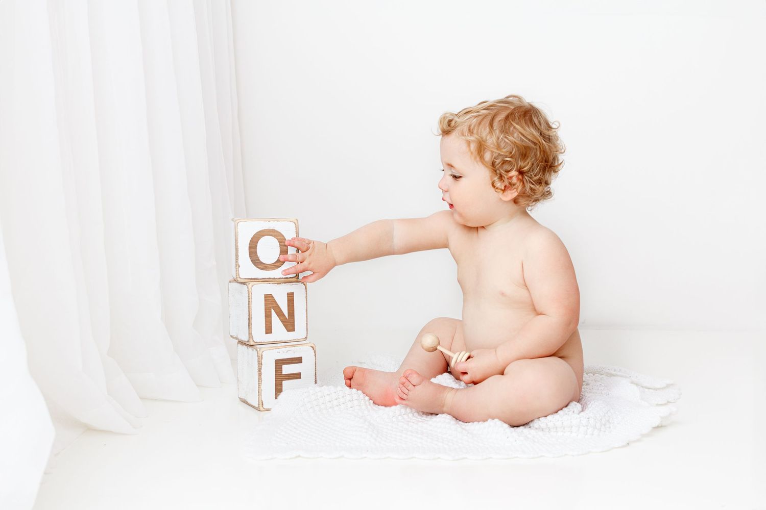 Baby plays with blocks during milestone photo session first year photos