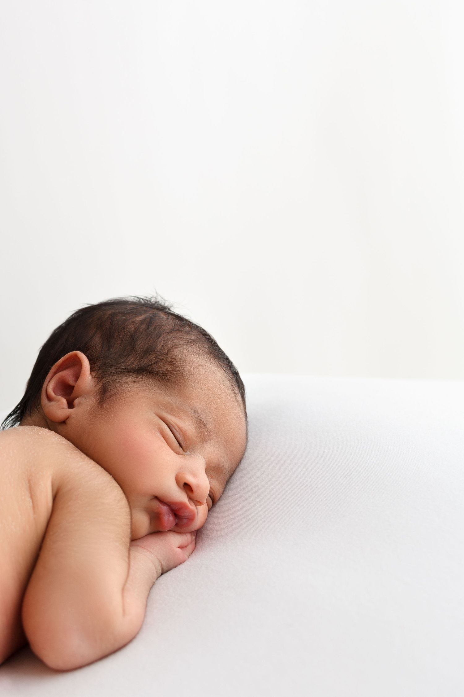 newborn baby sleeping peacefully on a beanbag during his first studio photos