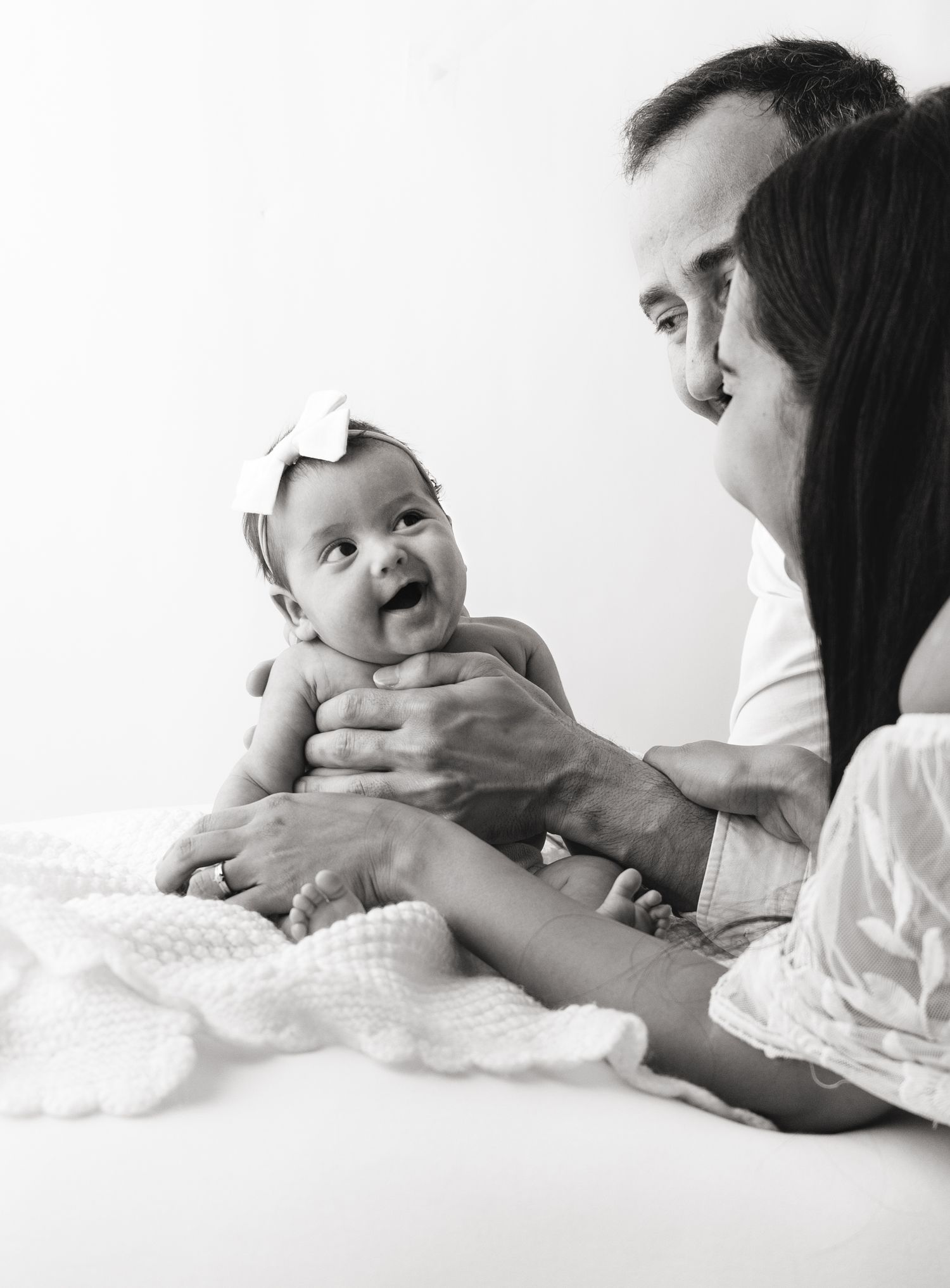 Cute 8 week old baby girl smiling up at mom and dad