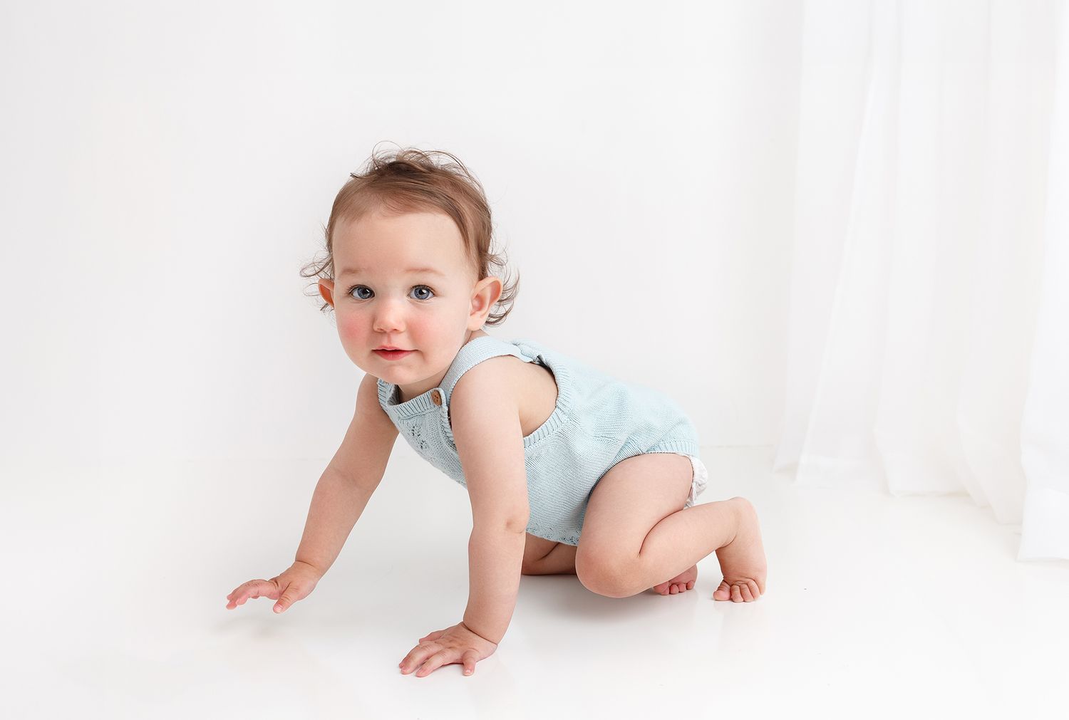 One year old crawling around during her first year photoshoot in the little white studio
