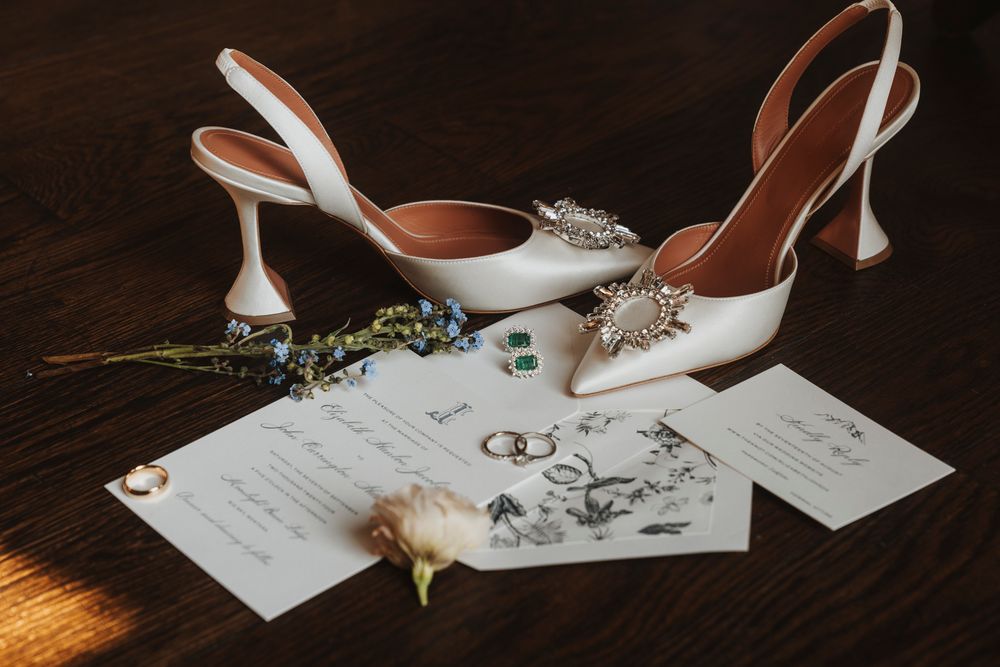 Wedding details including invitations and bridal accessories on dark wooden surface.