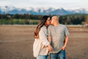 Couple sharing romantic moment on beach with mountain range in background.